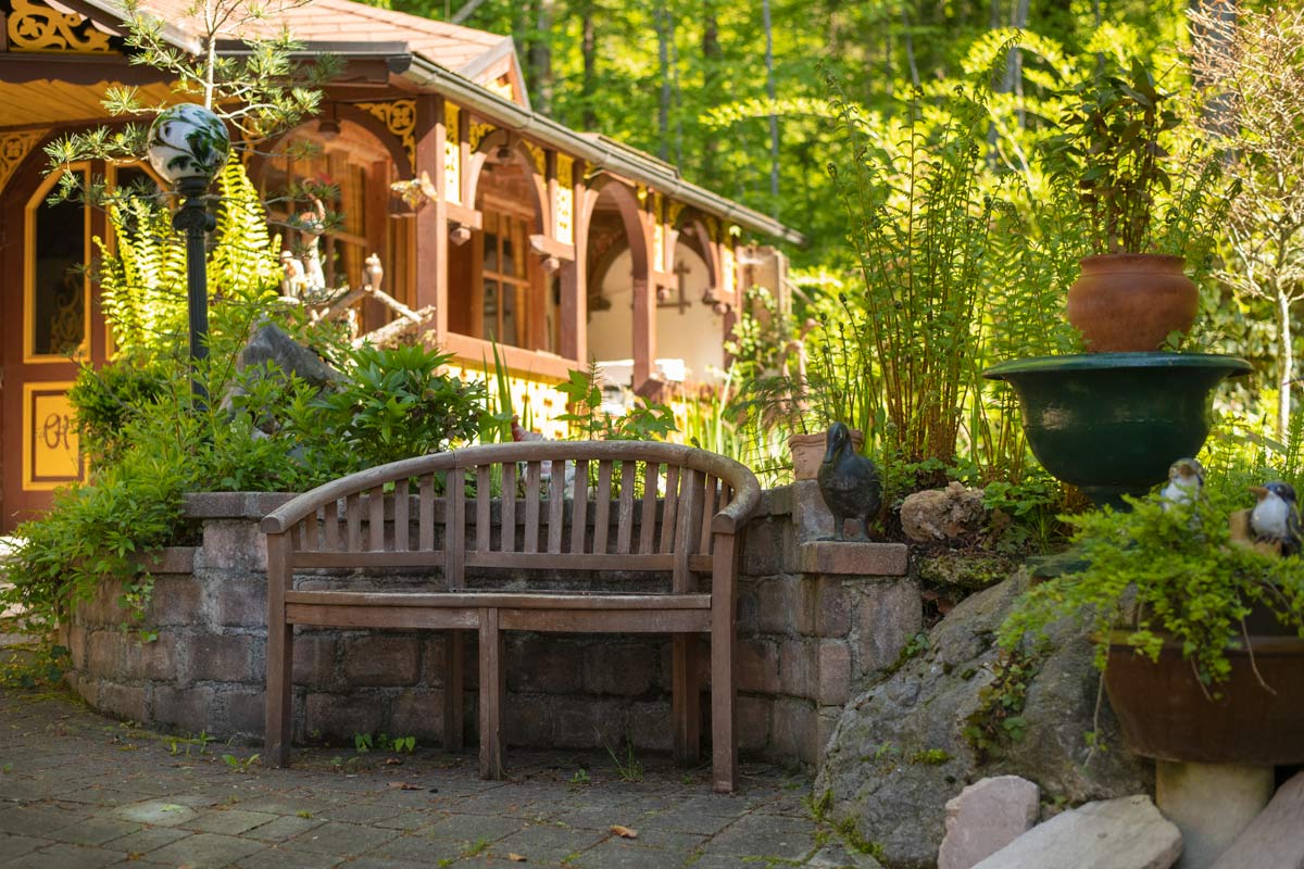 Holzbank im Innenhof vorm Teich mit Gartenfiguren und Pflanzen_private-Ferienwohnungen-Preisch_Bad-Ischl-im-Salzkammergut